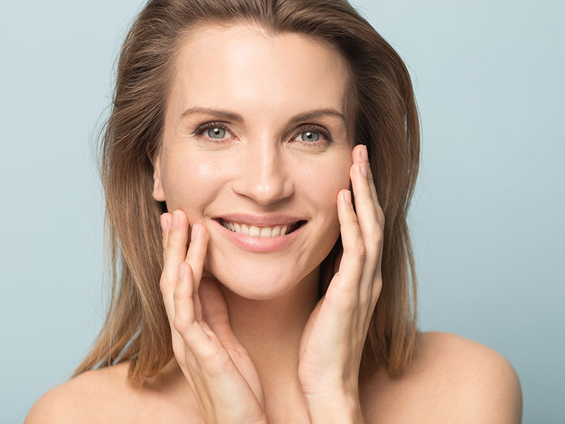 A woman smiling and touching her cheek