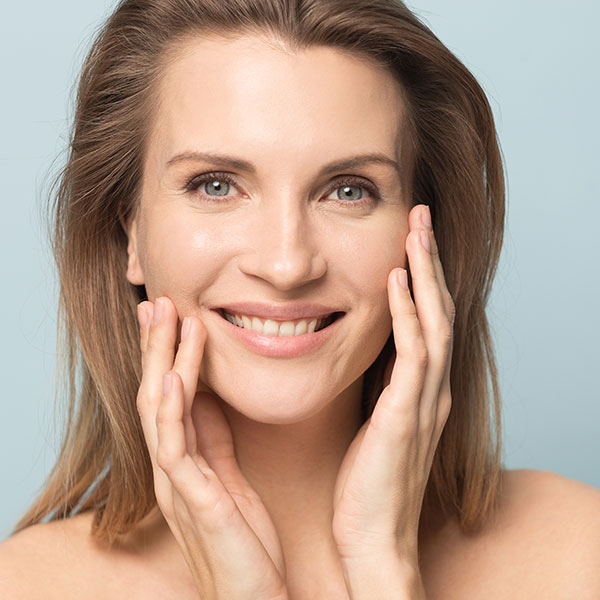A woman smiling and touching her cheeks