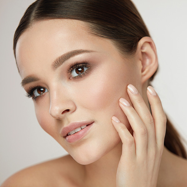 A woman smiling and touching her cheek